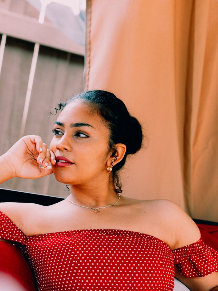 hero-gallery-03 Portrait of a young woman relaxing in a red polka dot dress in an outdoor setting.
