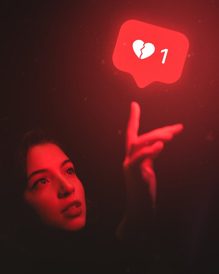 programs-03 Red-hued image of a woman reaching towards a broken heart icon symbolizing digital detachment.
